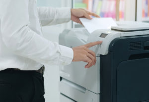 Office worker standing at refurbished printer